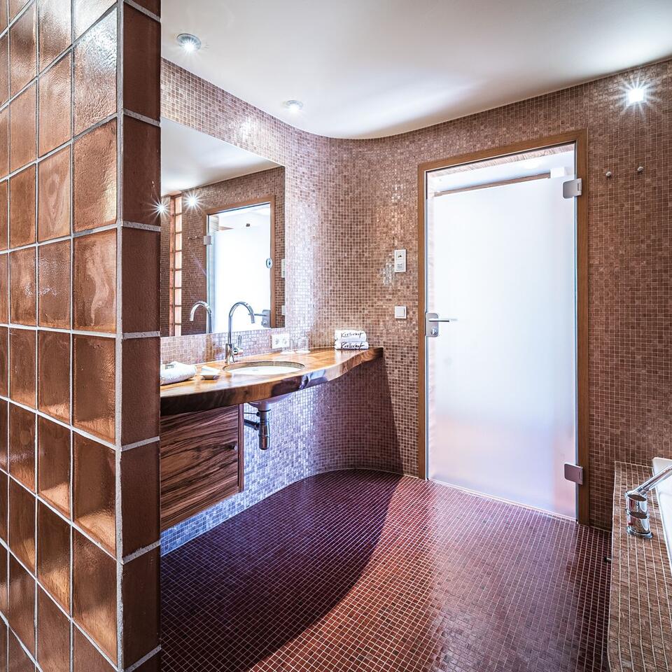 Modernes Badezimmer mit braunen Mosaikfliesen, Waschtisch und weißer Tür