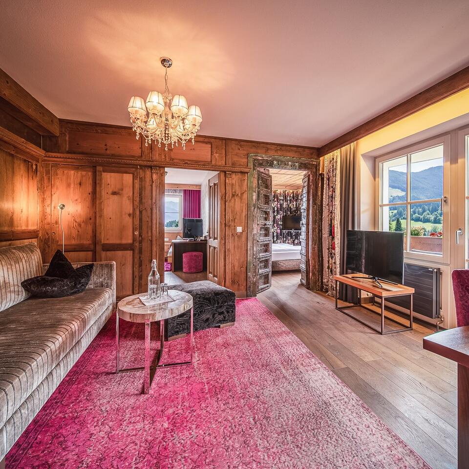 Living room with wood paneling, pink carpet and view into a bedroom