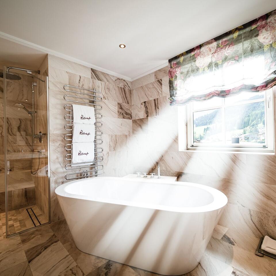 Bright bathroom with freestanding bathtub, towel warmer and marble tiles