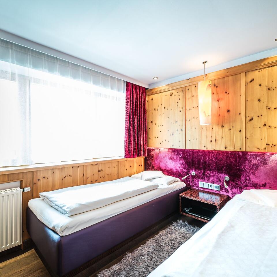 Bedroom with two beds, wood paneling and red accent