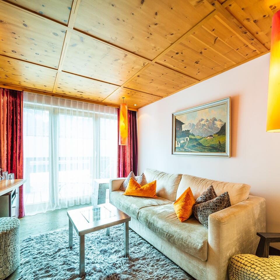 Living room with sofa, carpet, wooden beamed ceiling and window front