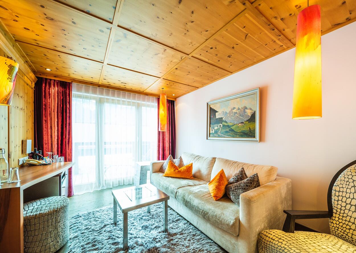 Wohnzimmer mit Sofa, Teppich, Holzbalkendecke und Fensterfront