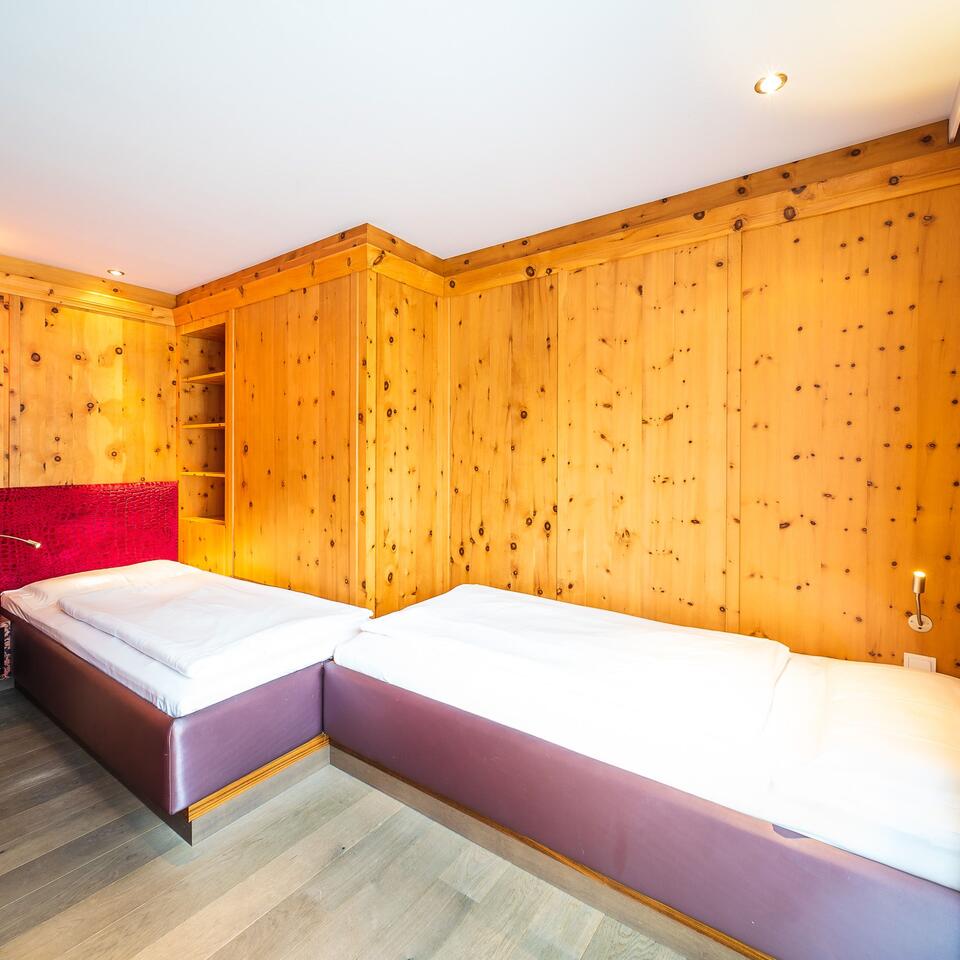 Wood-paneled room with two beds and red headboard