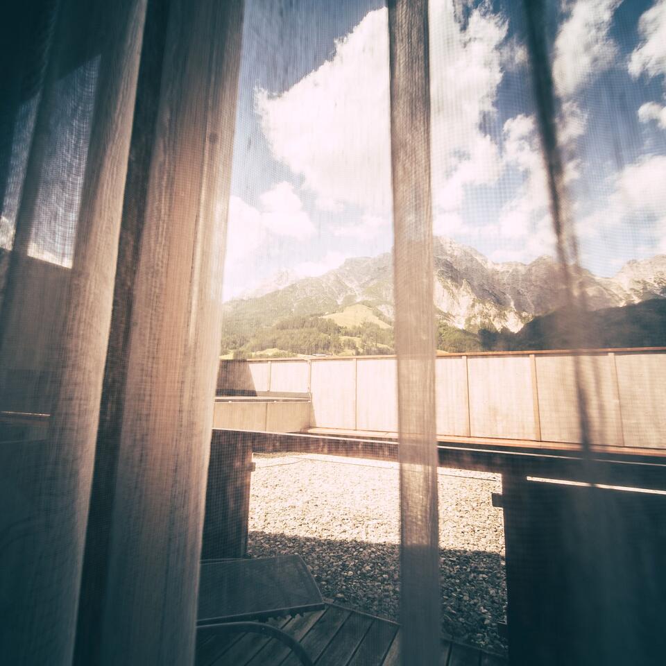 View through curtain onto balcony, mountains and sky