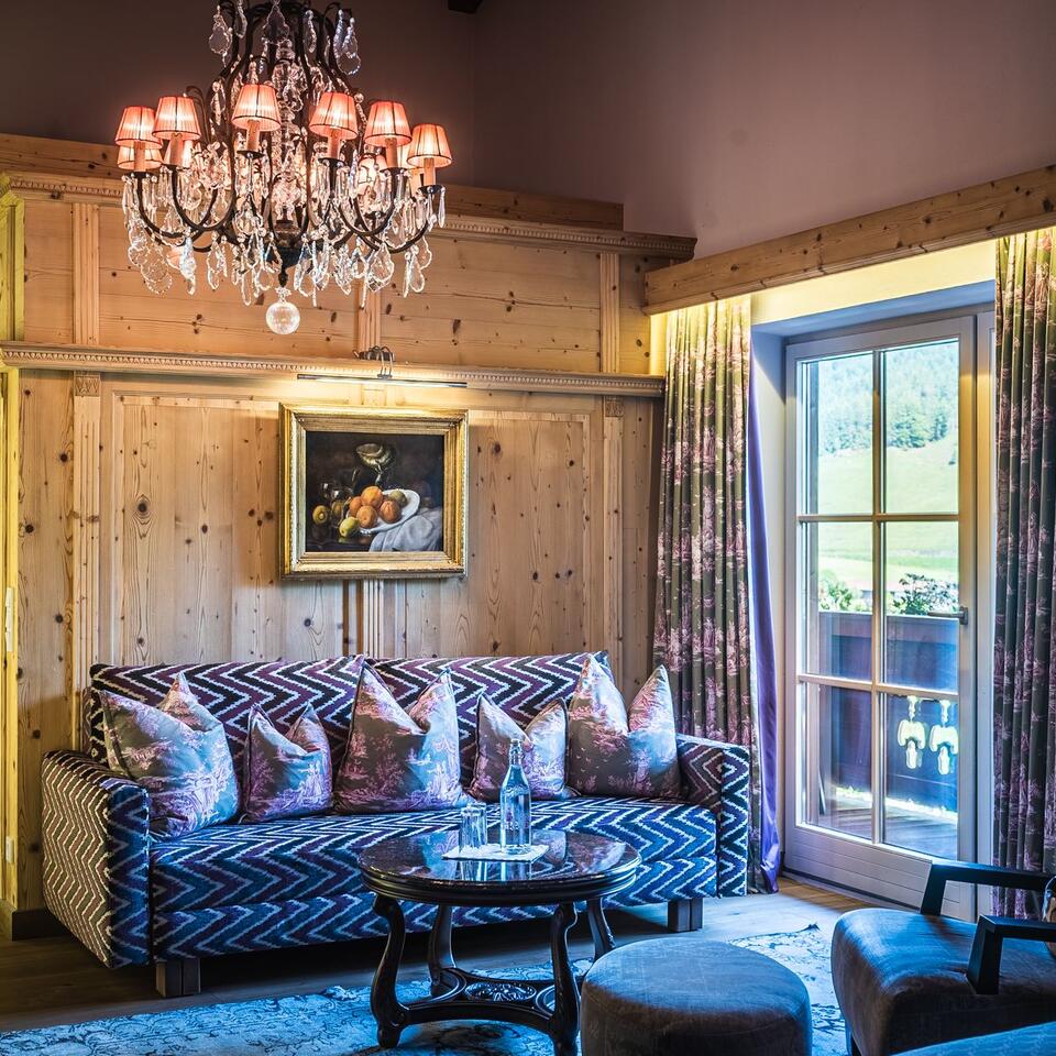Holzvertäfeltes Wohnzimmer mit Sofa, Kristalllüster und Balkontür