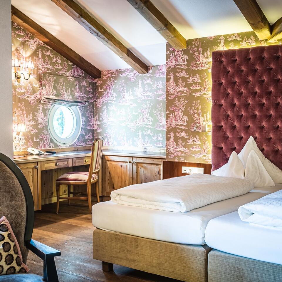Hotelzimmer mit Doppelbett, Schreibtisch und gemusterter Tapete