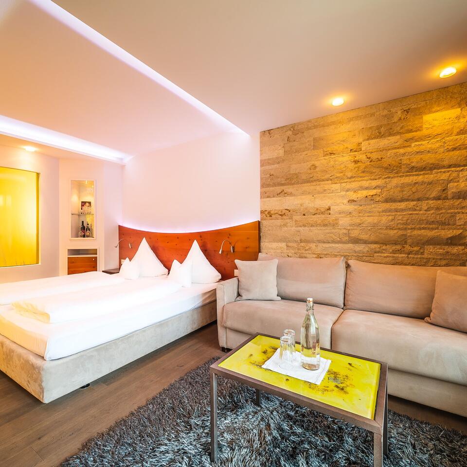 Hotelzimmer mit Bett, Sofa, Tisch und dekorativer Wand