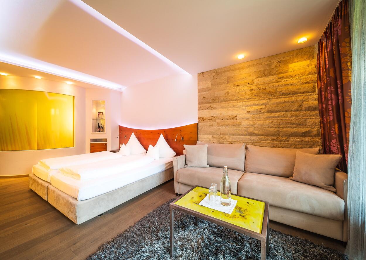 Hotelzimmer mit Bett, Sofa, Tisch und dekorativer Wand