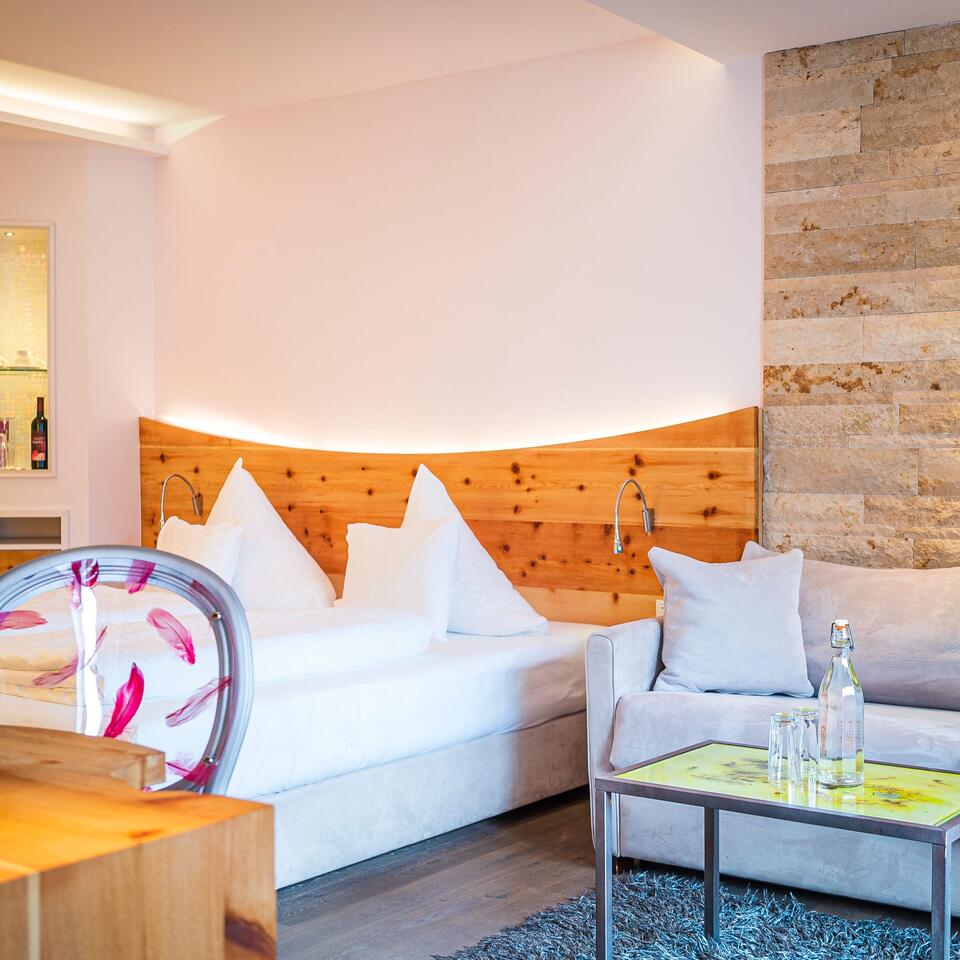Helles Hotelzimmer mit Doppelbett, Sofa, Tisch und Holzwand