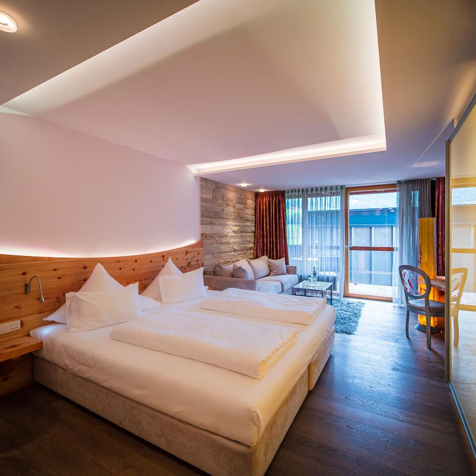 Helles Hotelzimmer mit Doppelbett, Sitzecke und Schreibtisch