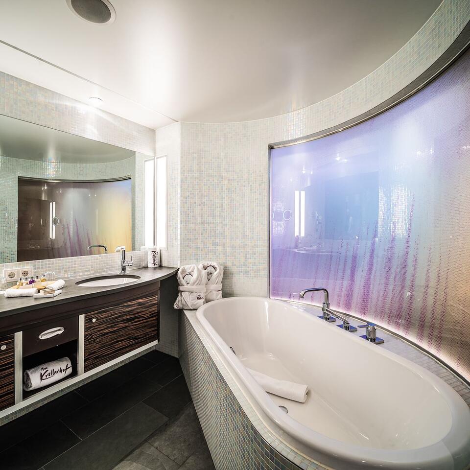 Modernes Badezimmer mit Badewanne, Waschtisch und großem Spiegel