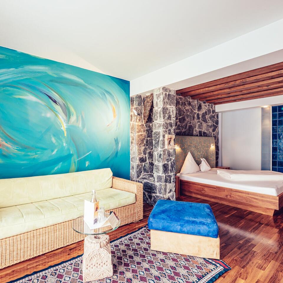Hotelzimmer mit Sofa, Bett und blauem Wandbild