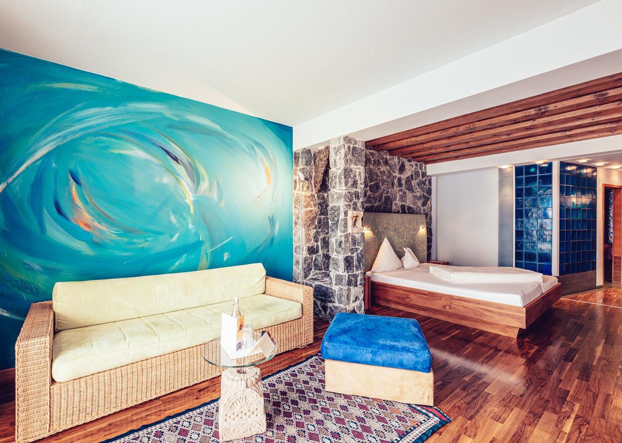 Hotelzimmer mit Sofa, Bett und blauem Wandbild