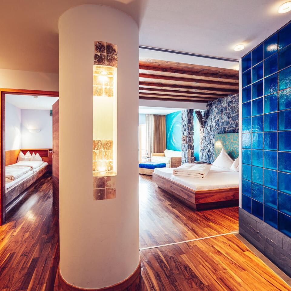 Hotelzimmer mit Holzboden, Säule mit Lampe und Blick auf Bett und Bad