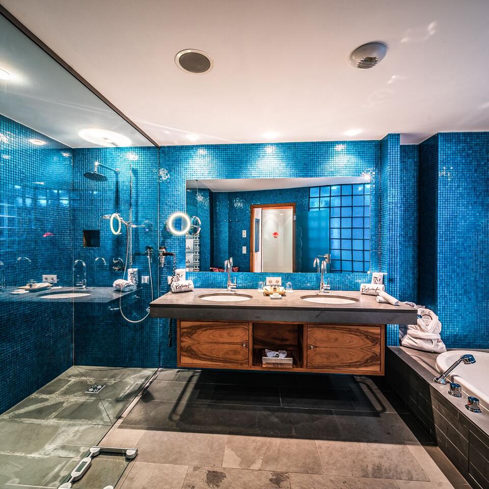 Blaues Badezimmer mit Doppelwaschbecken, Spiegel, Dusche und Badewanne