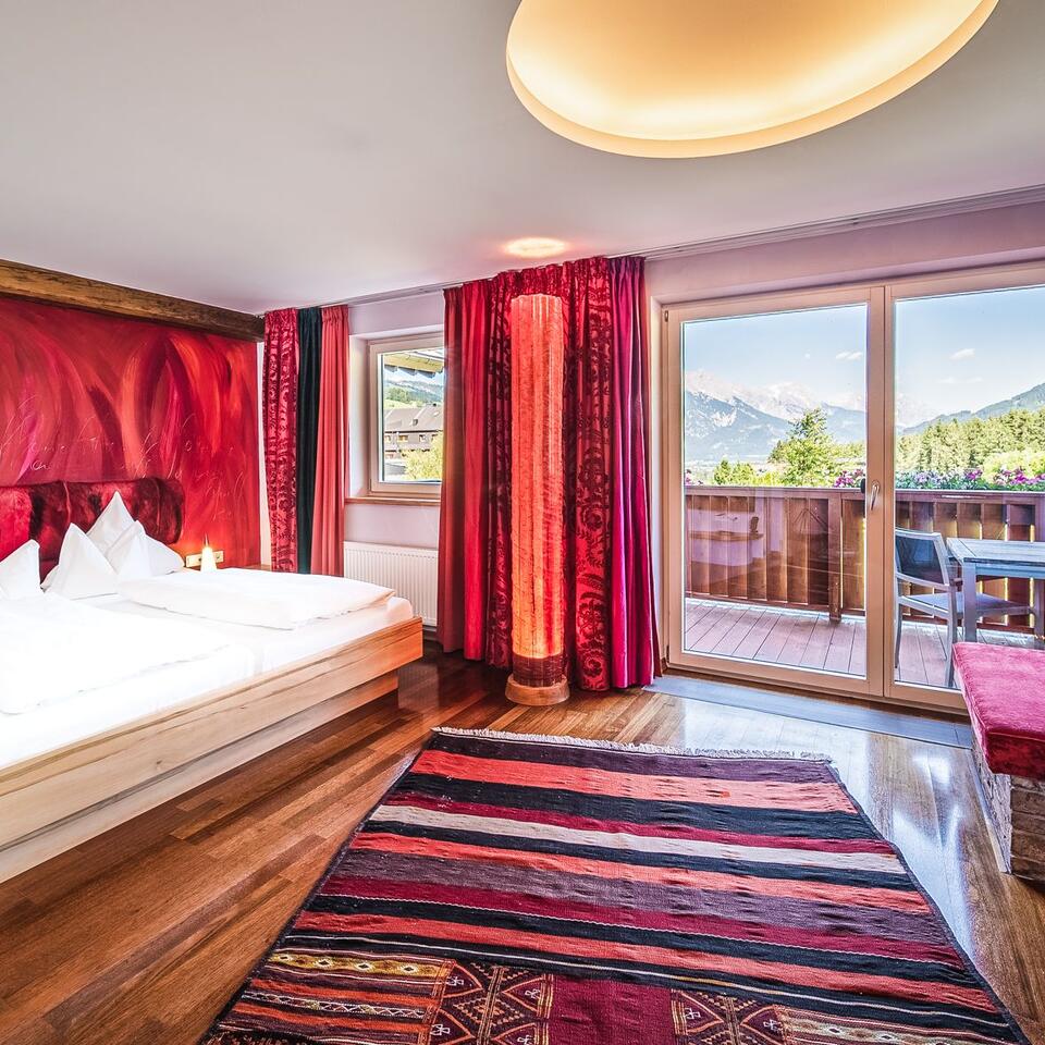 Bedroom with red wall, carpet and balcony with mountain view