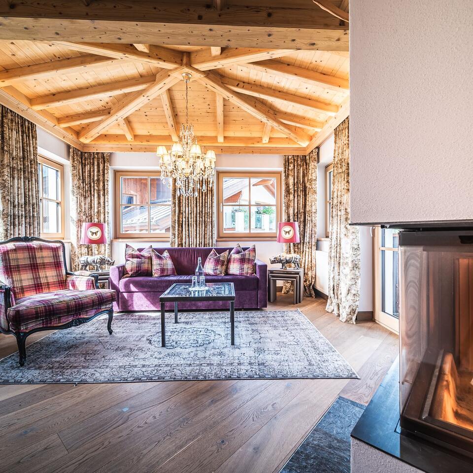 Cozy living room with wooden beamed ceiling, fireplace and purple sofa