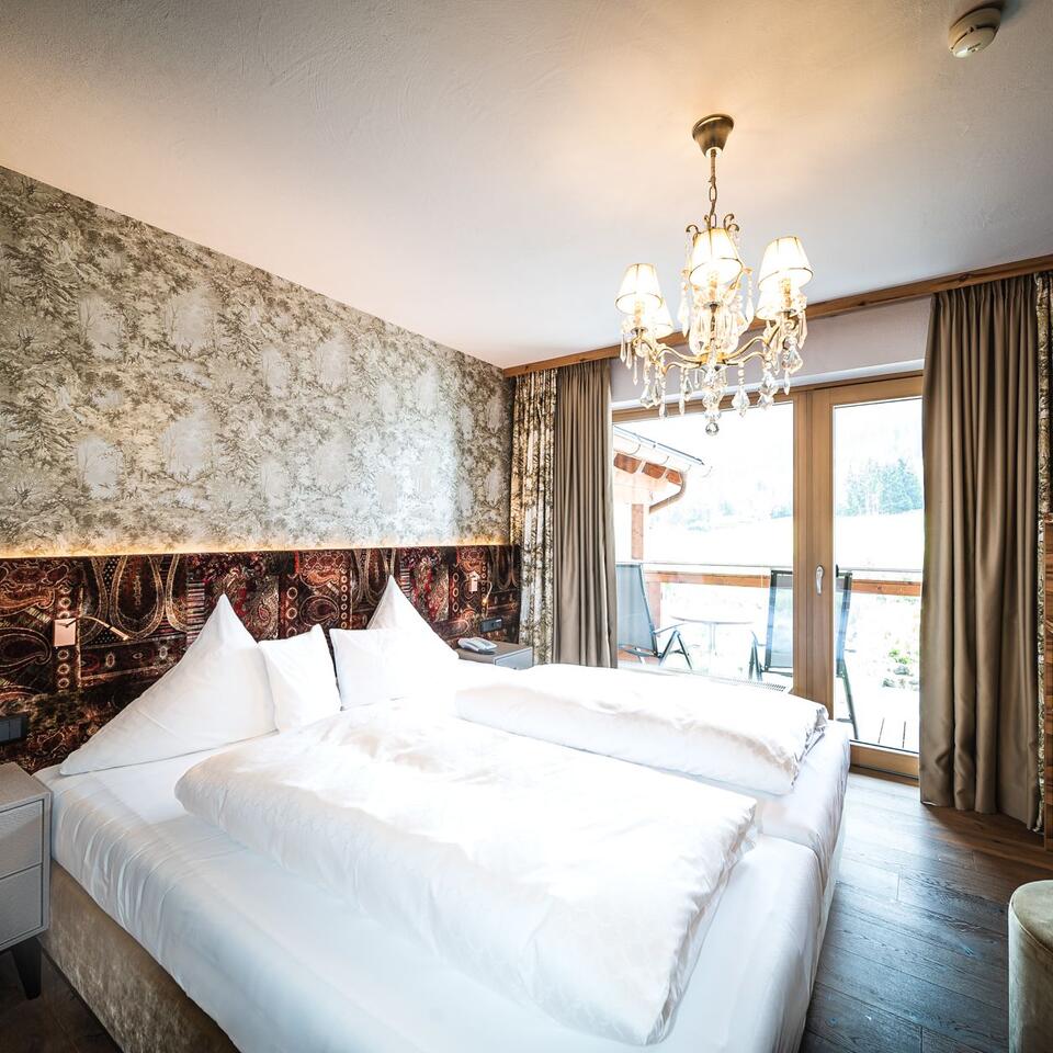 Bright bedroom with double bed, wallpaper, chandelier and balcony
