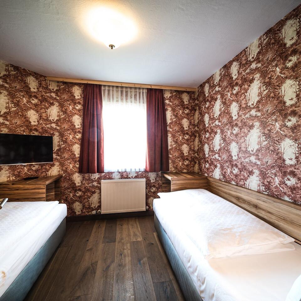 Hotel room with two beds, patterned wallpaper and window