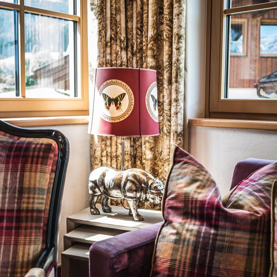 Cozy seating area with checkered armchair, cushions, lamp with butterfly and rhinoceros figure