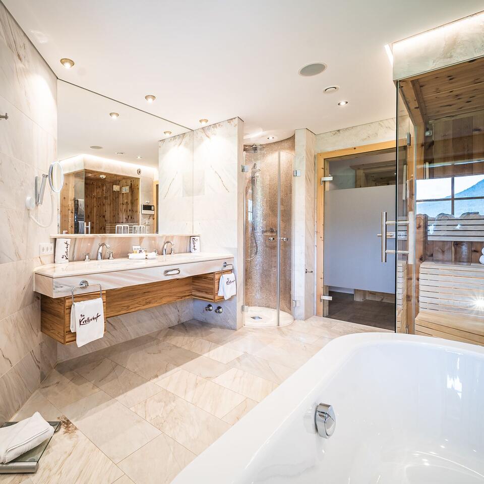 Bright bathroom with bathtub, shower, sink and sauna