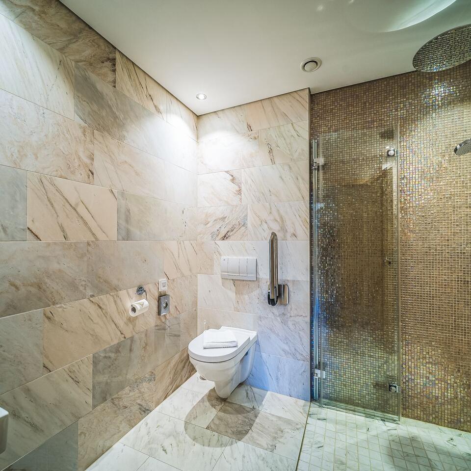 Modern bathroom with marble tiles, toilet and shower cubicle