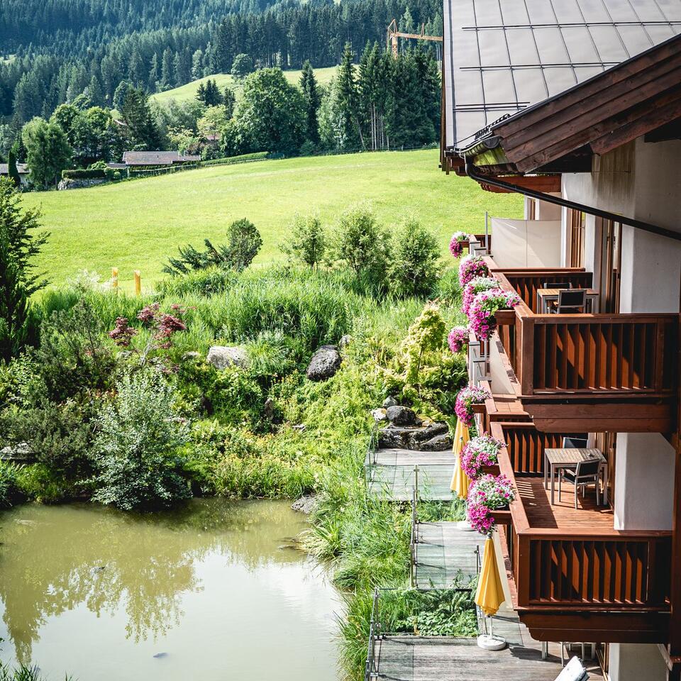 Balconies of a hotel overlooking a pond and green hills