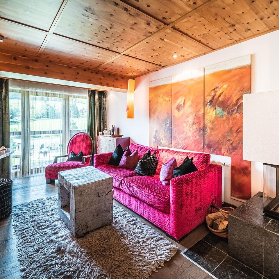 Living room with red sofa, wooden table, artwork and wooden beamed ceiling