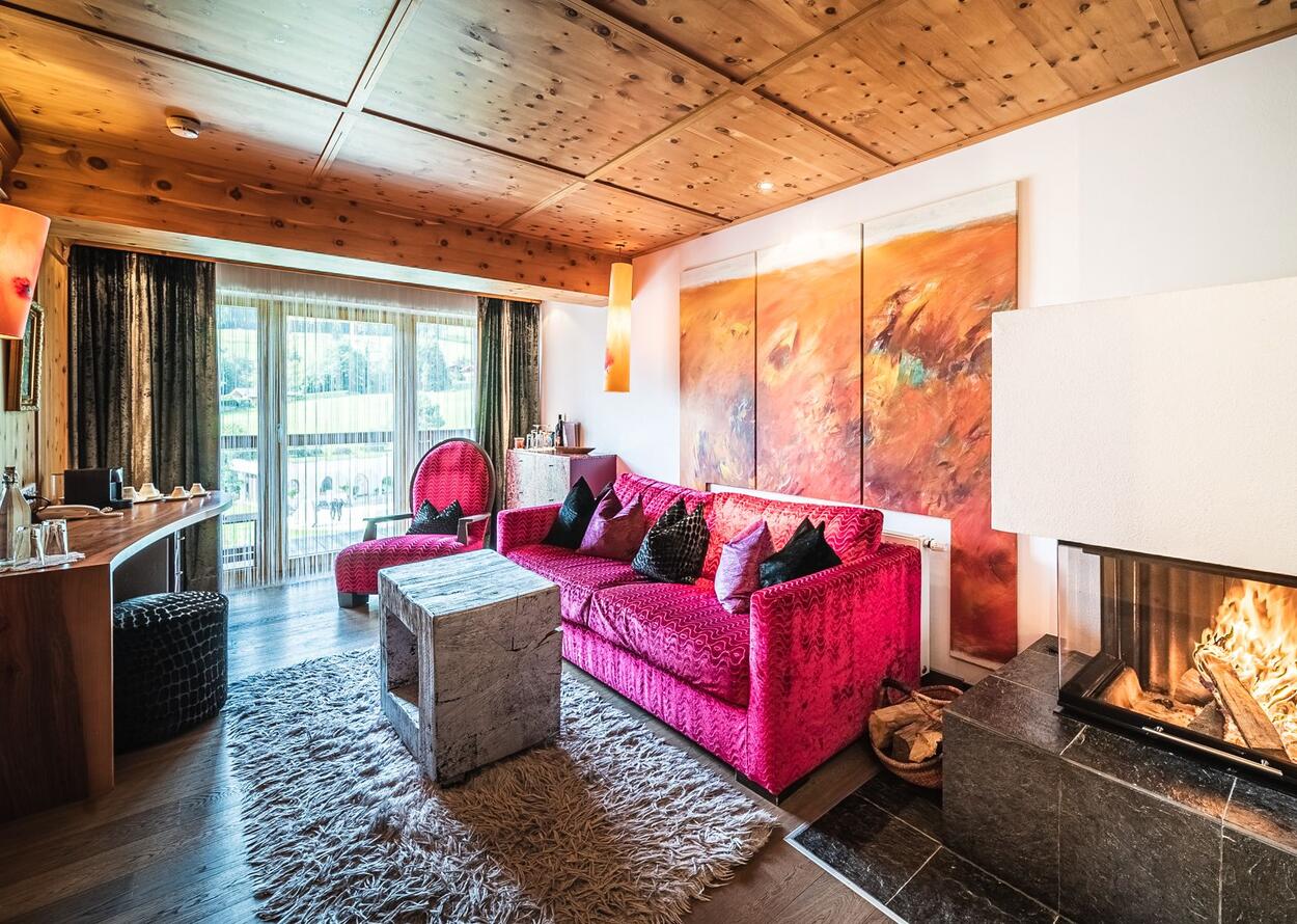 Wohnzimmer mit rotem Sofa, Holztisch, Kunstwerk und Holzbalkendecke