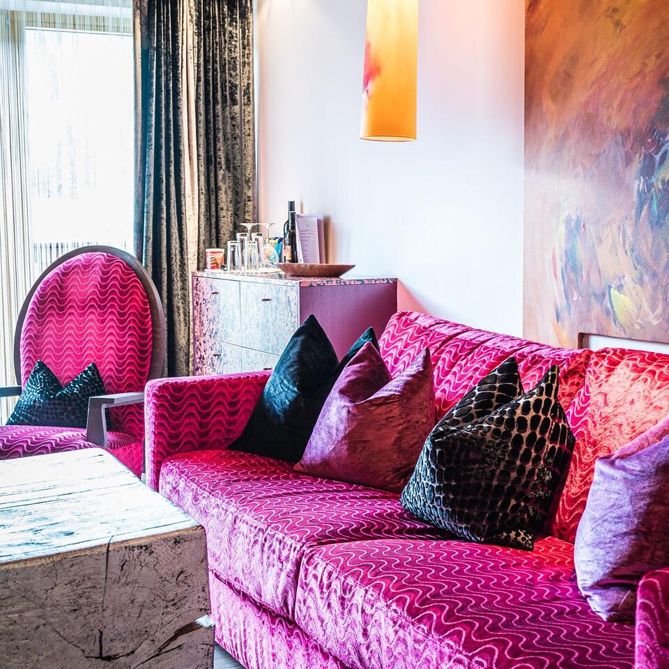 Pink living room with sofa, armchair, table and artwork on the wall