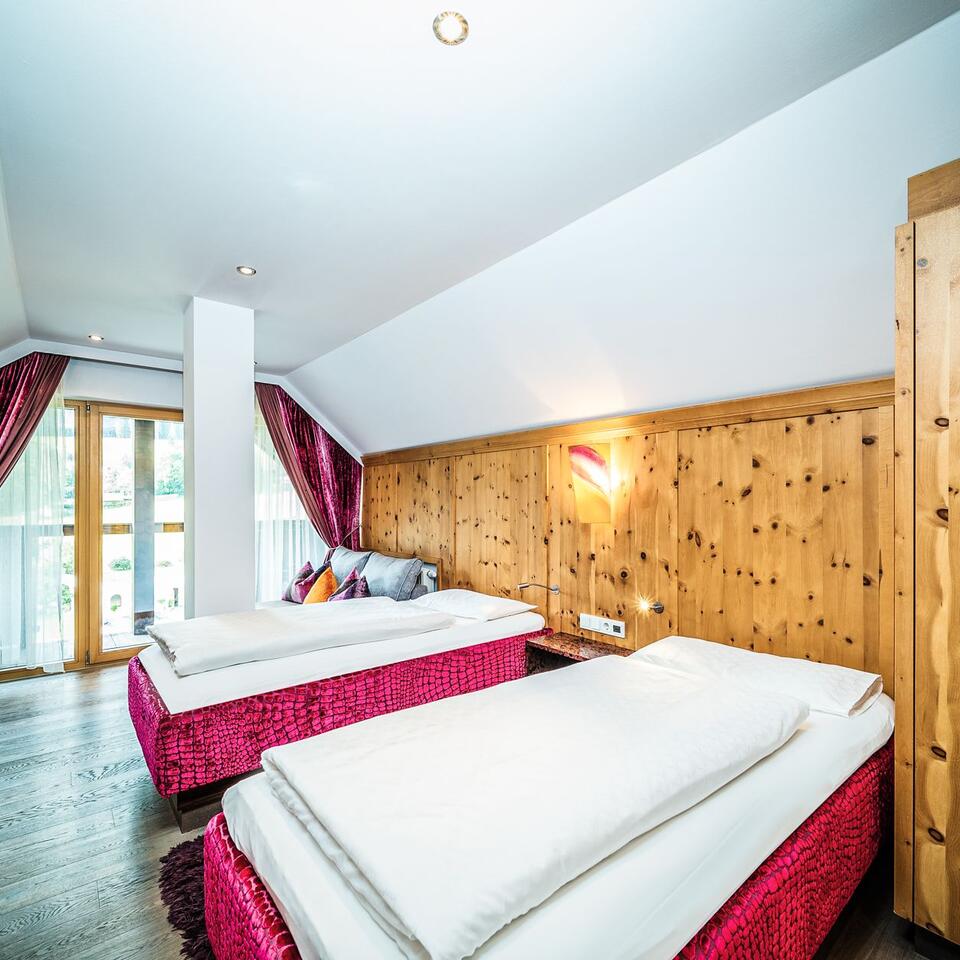 Two beds in a room with wood paneling and sloping ceilings