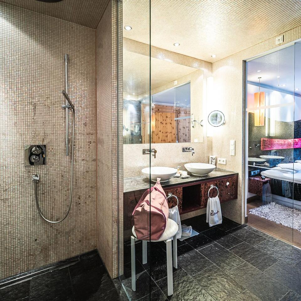 Modern bathroom with shower, sink and view of a bedroom