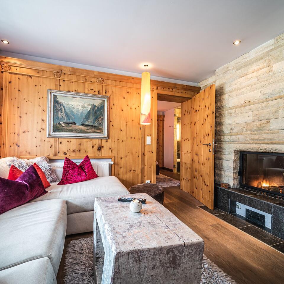 Wohnzimmer mit Holzwand, weißer Couch, Kamin und Gemälde