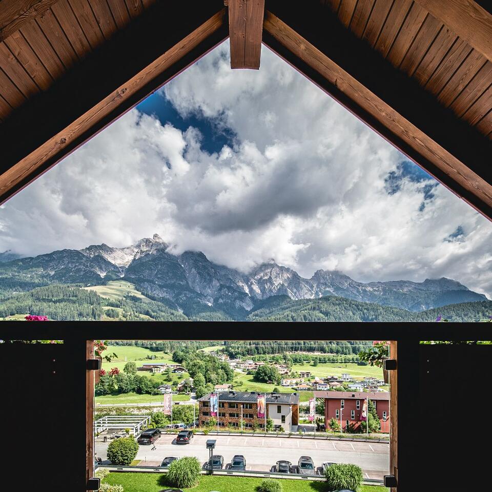 Blick aus Dachfenster auf Berge, Wolken und grüne Landschaft mit Häusern