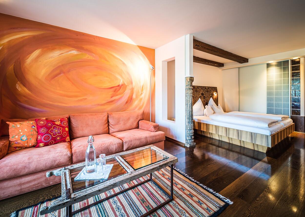 Gemütliches Hotelzimmer mit Sofa, Couchtisch, Teppich und Doppelbett