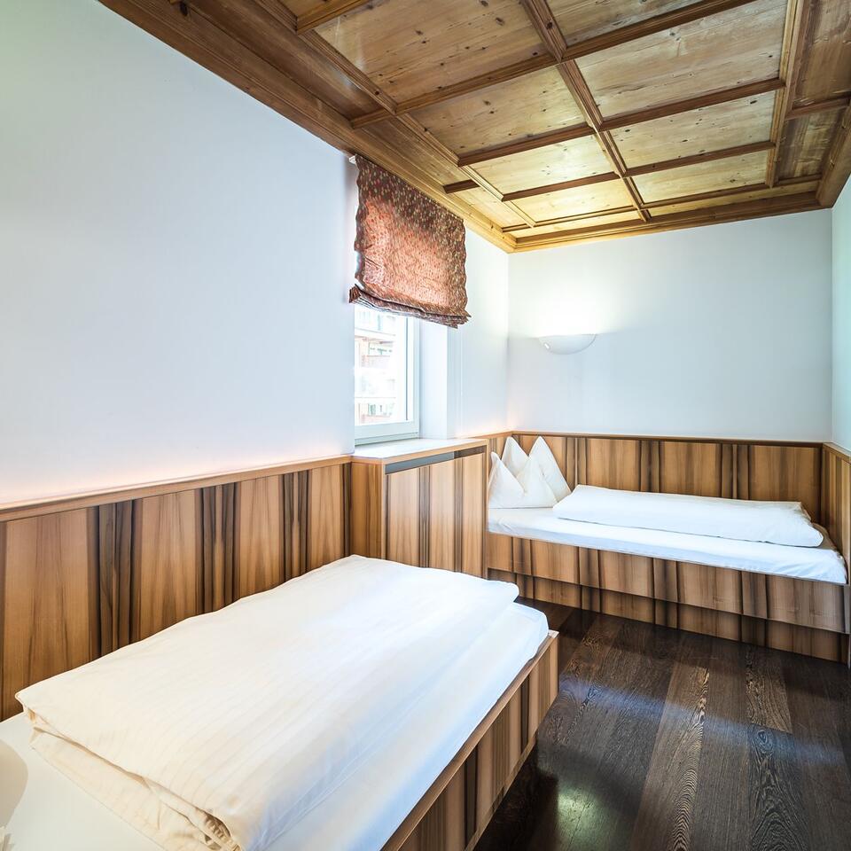Room with two beds, wood paneling and ceiling with wooden beams