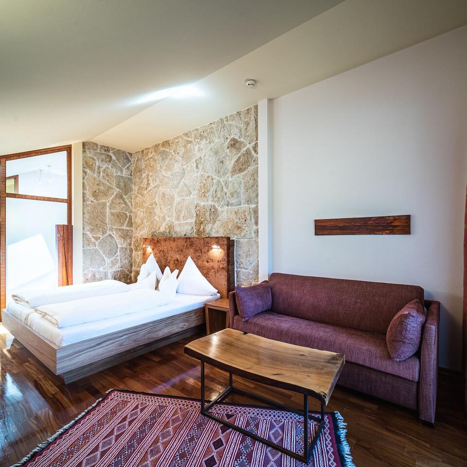 Hotel room with double bed, sofa, wooden table and patterned wall
