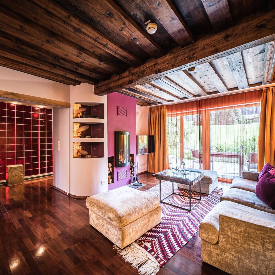 Living room with wooden beamed ceiling, red wall, fireplace, sofa, carpet and view of terrace