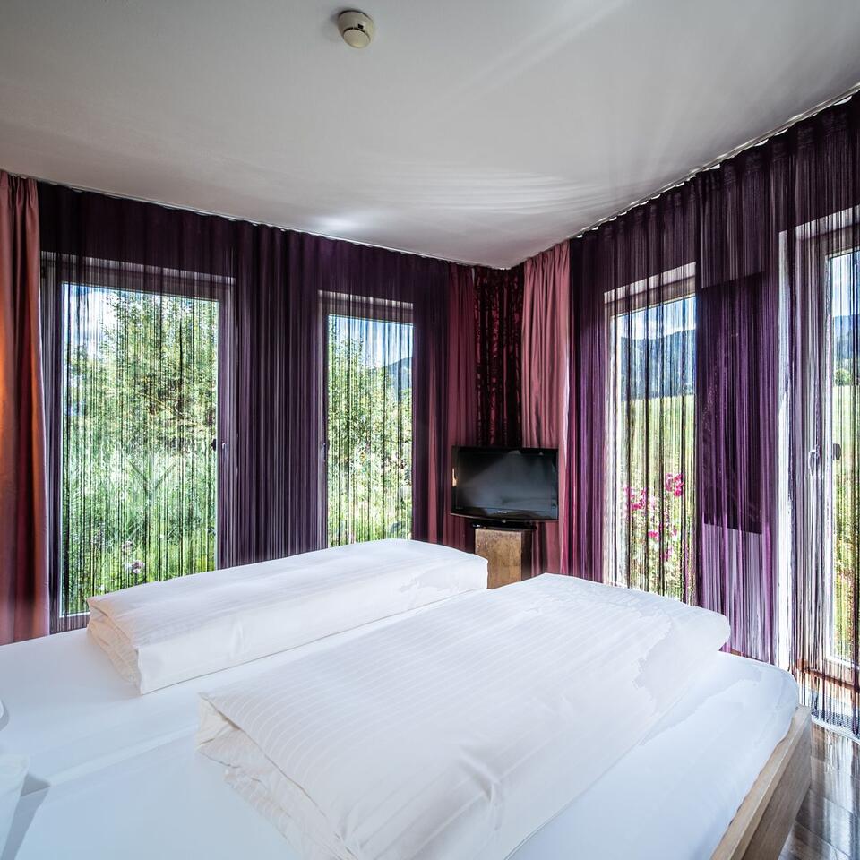Bedroom with double bed, curtains and view of the greenery