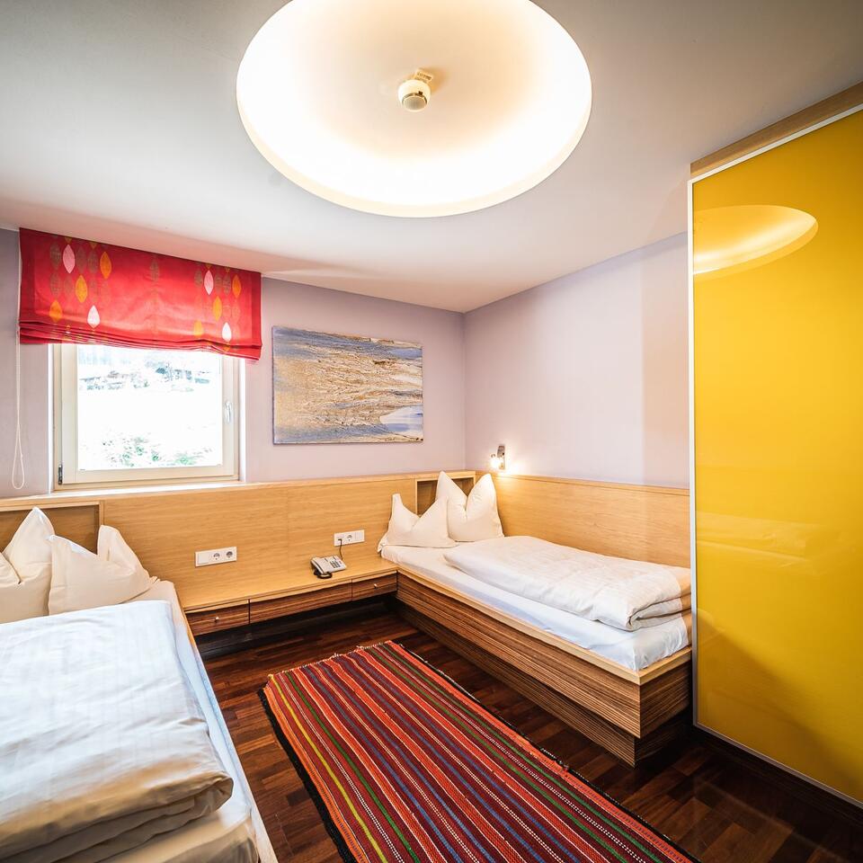 Bedroom with two single beds, red carpet and yellow wardrobe
