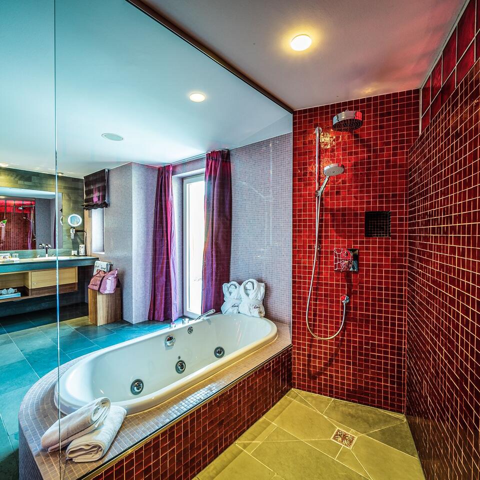 Modern bathroom with red mosaic wall, bathtub and shower