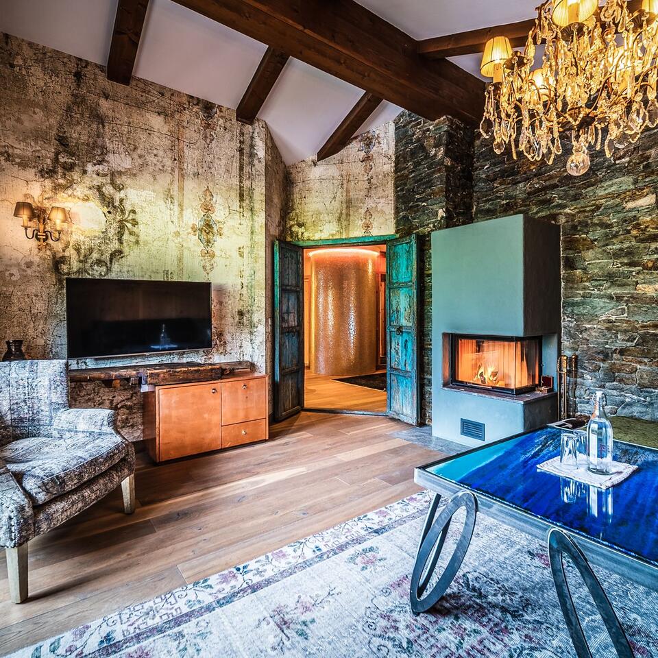 Rustikales Wohnzimmer mit Kamin, Fernseher, Holzbalken und Kronleuchter