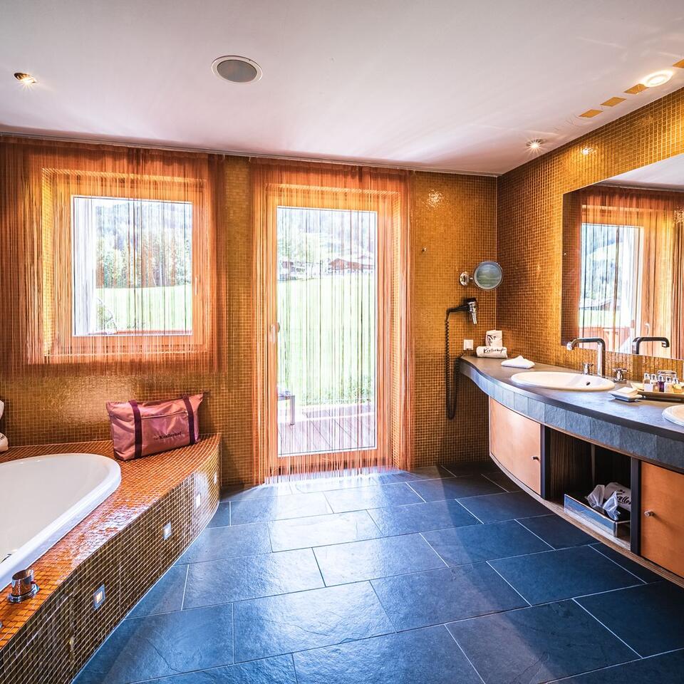 Modernes Badezimmer mit Badewanne, Doppelwaschbecken und Fenster mit Blick ins Grüne