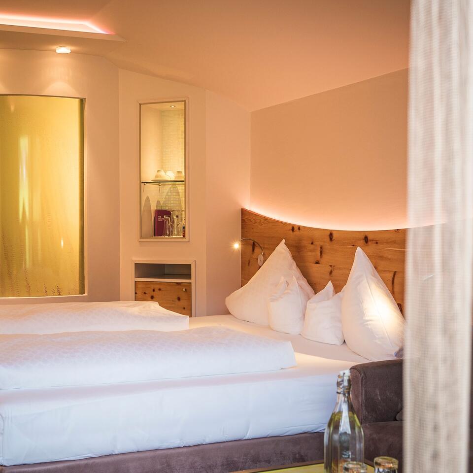 Hotelzimmer mit Doppelbett, Nachttisch und indirekter Beleuchtung