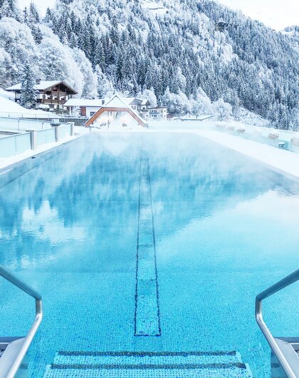 Beheizter Pool vor verschneiter Berglandschaft in Tirol