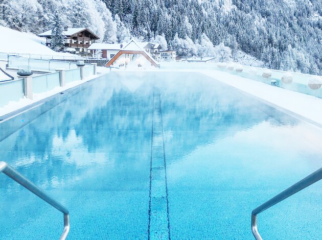 Beheizter Pool vor verschneiter Berglandschaft in Tirol