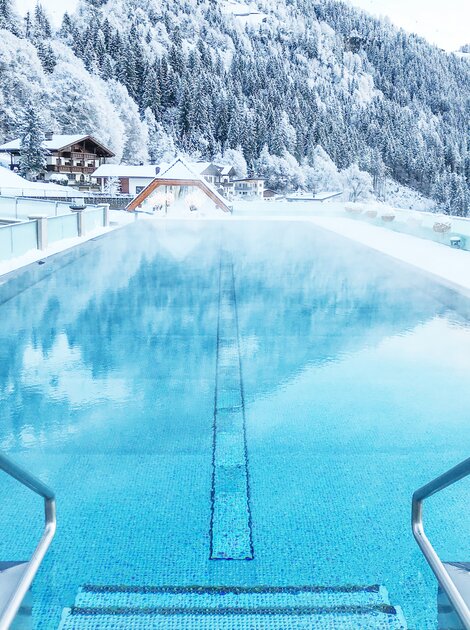 Beheizter Pool vor verschneiter Berglandschaft in Tirol