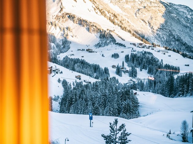 Verschneite Landschaft in Vorarlberg mit Bergen, Bäumen und Häusern im Winter